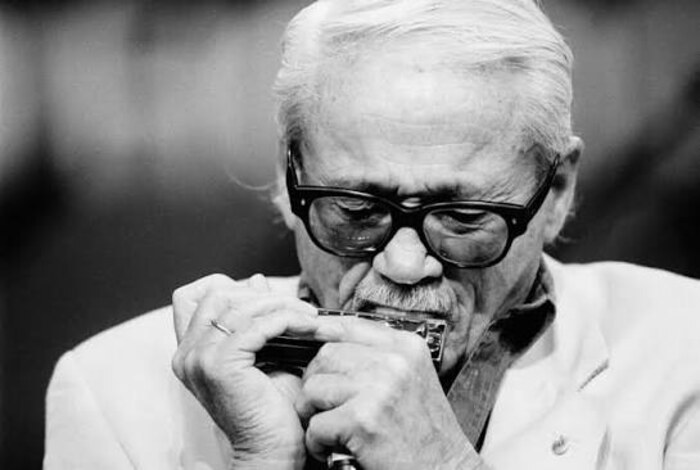 Gros plan de Toots Thielemans jouant de l'harmonica, yeux fermés